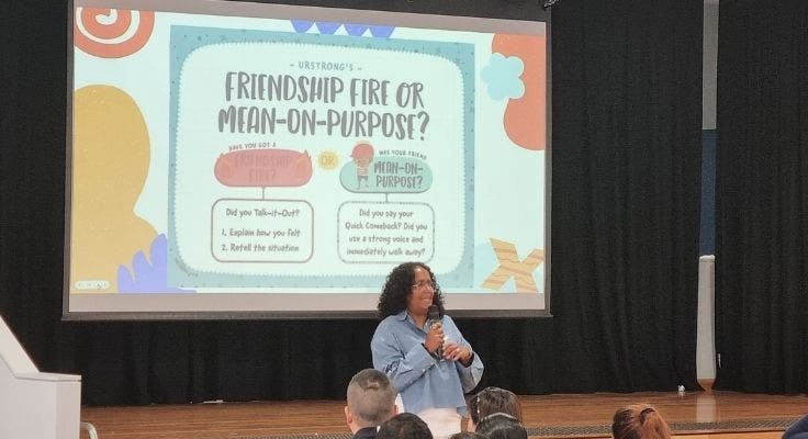 School Chaplain addressing parents in frond of a slide displaying Friendship Fire or Mean-on-Purpose?