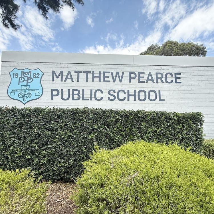 Matthew Pearce Public School sign and crest on wall behind hedges