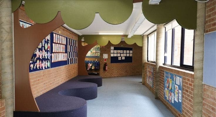 School building corridor with wooden tree up wall and across roof and artworks on the walls