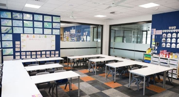Classroom with tables and chairs set out and whiteboard and artworks on the wall