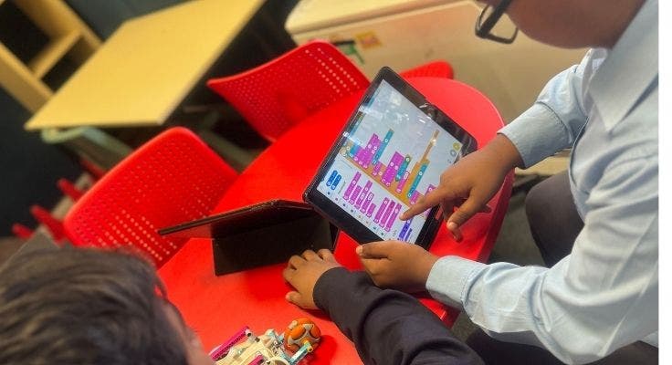 Students using an iPad to create block code