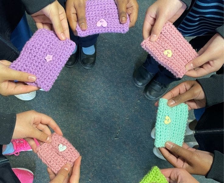 Crochet squares held by students standing in a circle